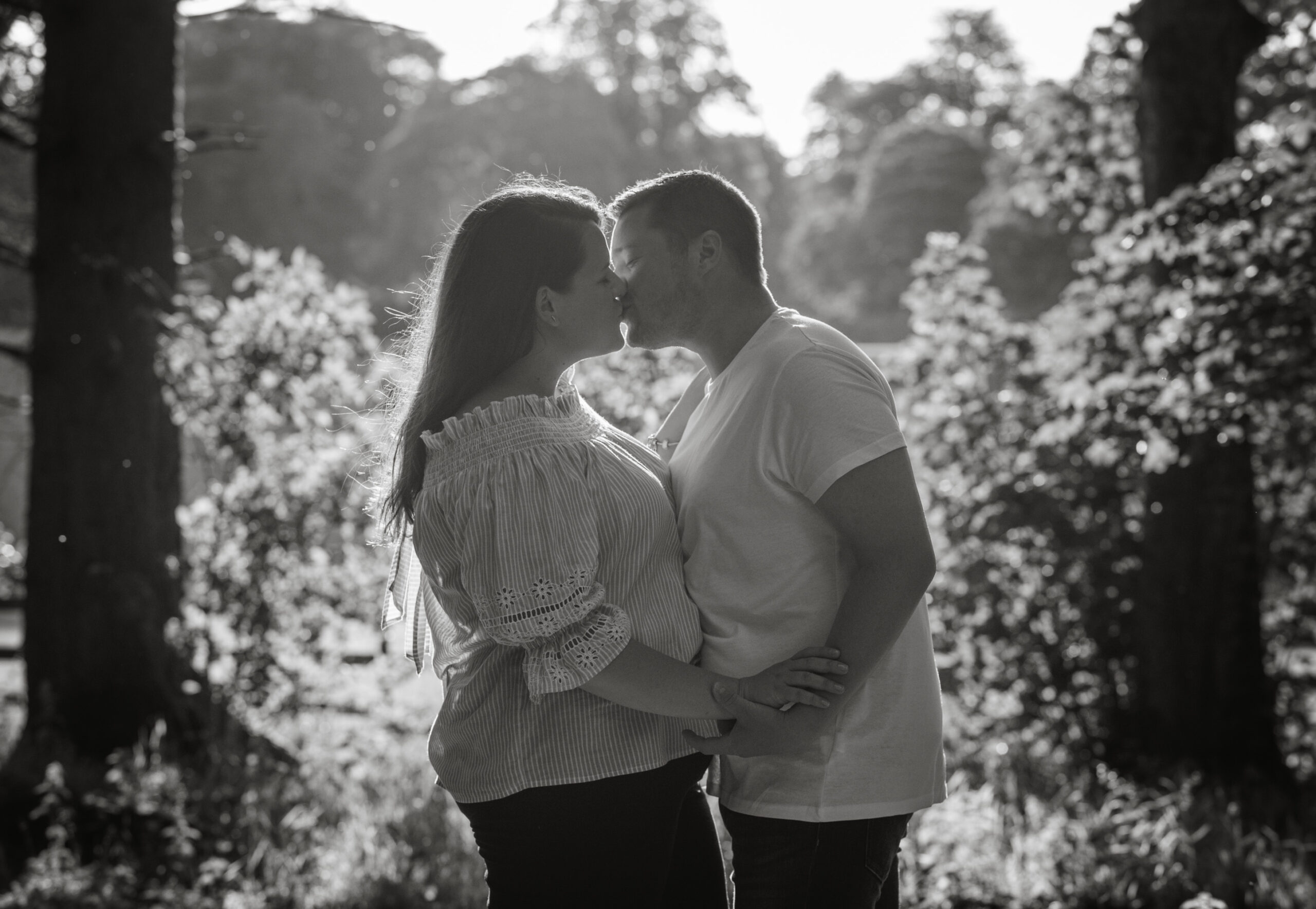 A couple kiss at sunset during their engagement photo shoot by Zoe Rae