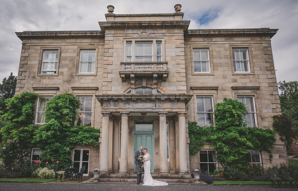 The front of Netherdale House as a married couple pose for their wedding photo