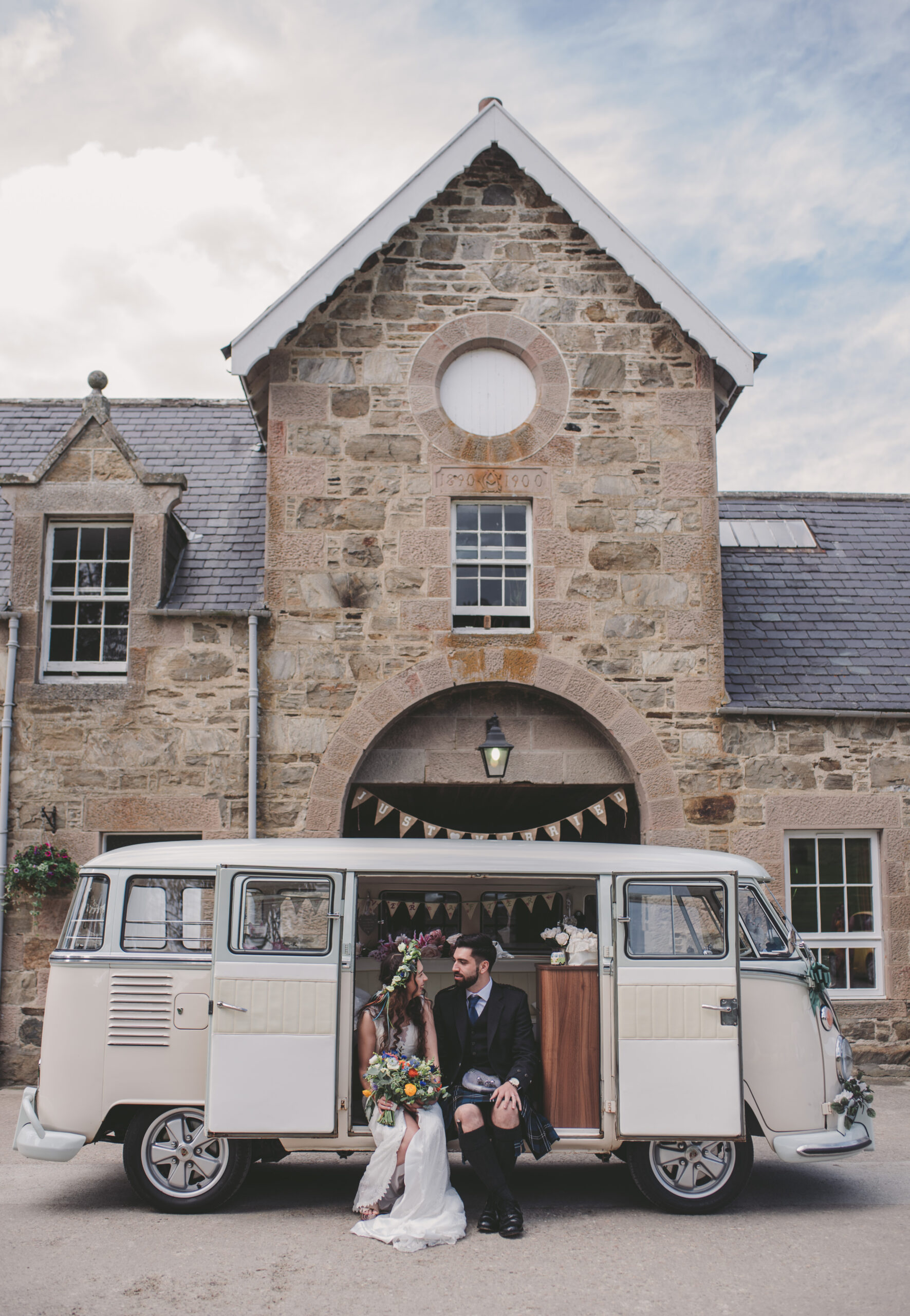 A bride and groom sit in a VW camper van in front of Aswanley after their wedding