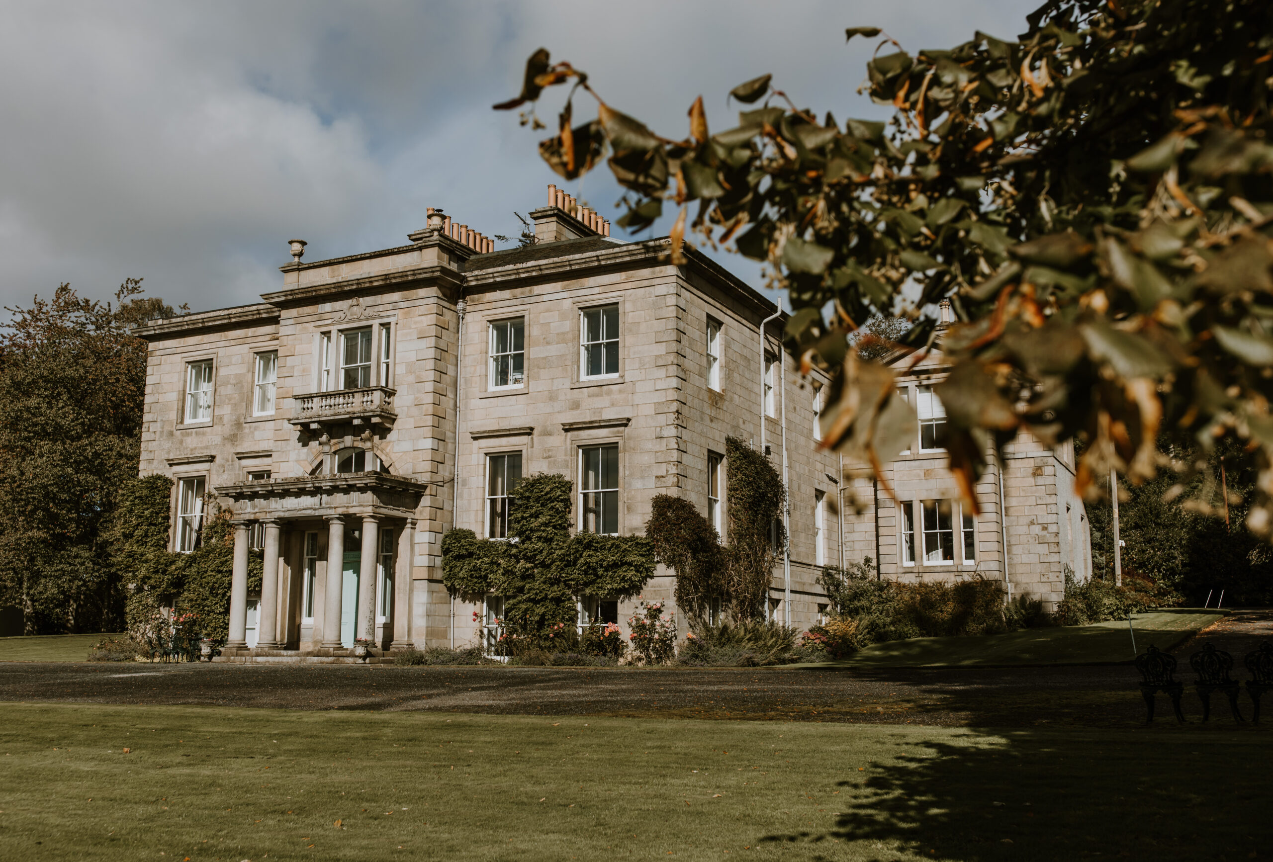 Netherdale House taken in autumn from behind some trees by Zoe Rae Photography