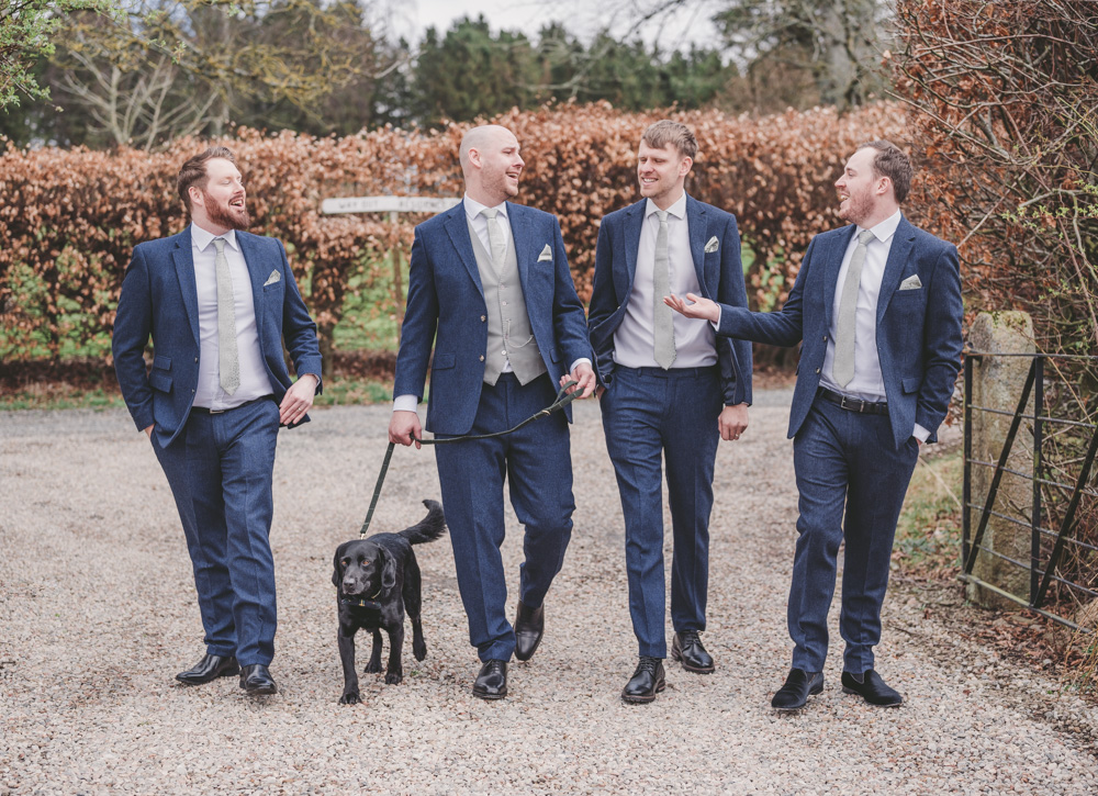 The groom and his friends take a walk with his black lab the morning of the wedding